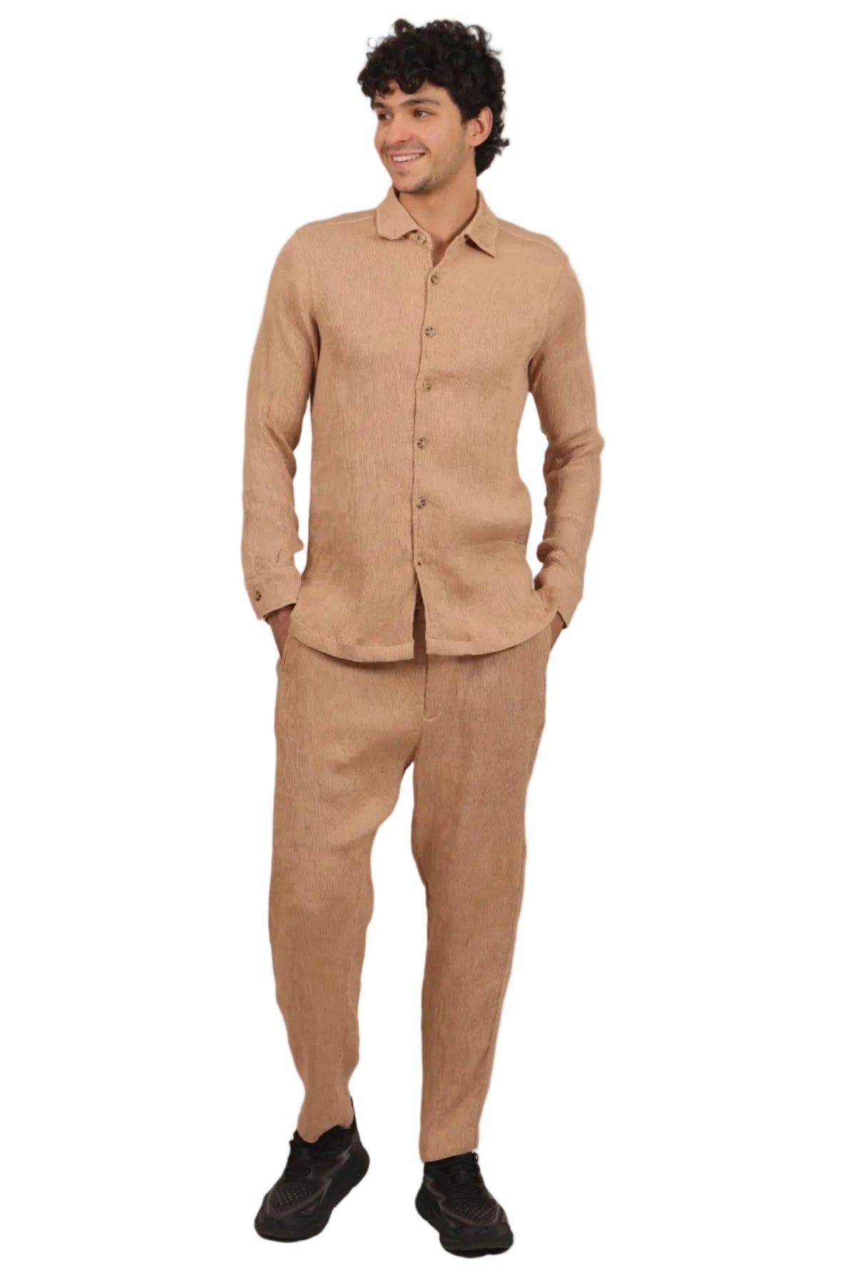 Man wearing a beige shirt and pants on a plain background