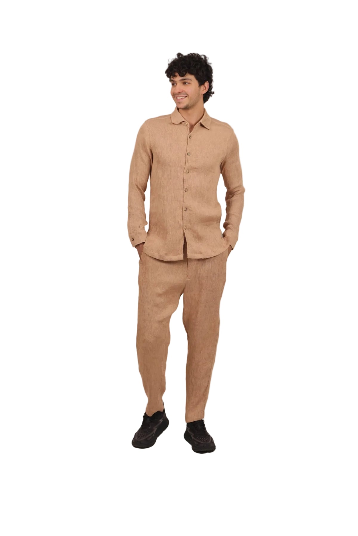 Man wearing a beige shirt and pants on a plain background